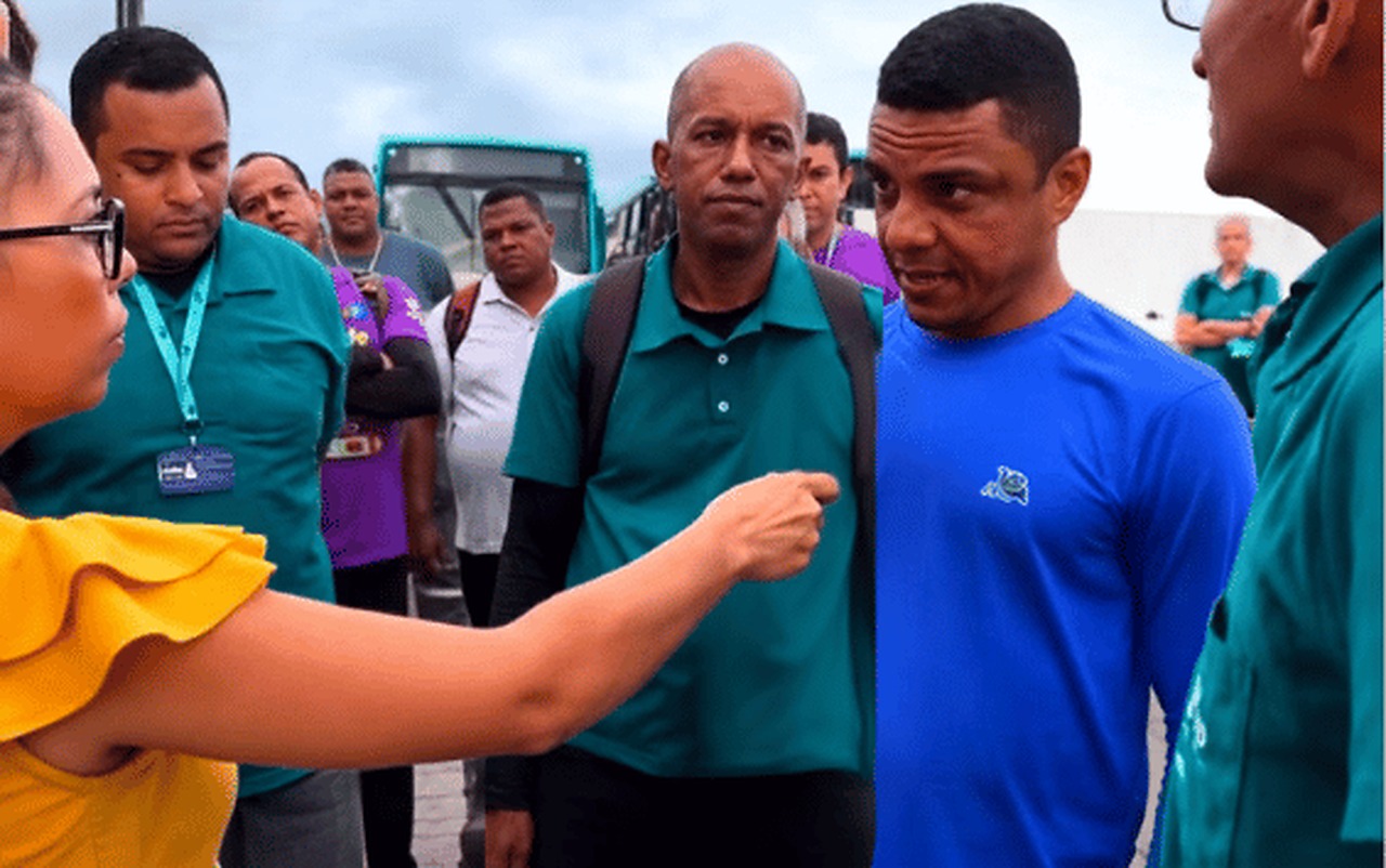 Trabalhador da VRS fala durante entrevista em frente a ônibus, acompanhado por outros funcionários
