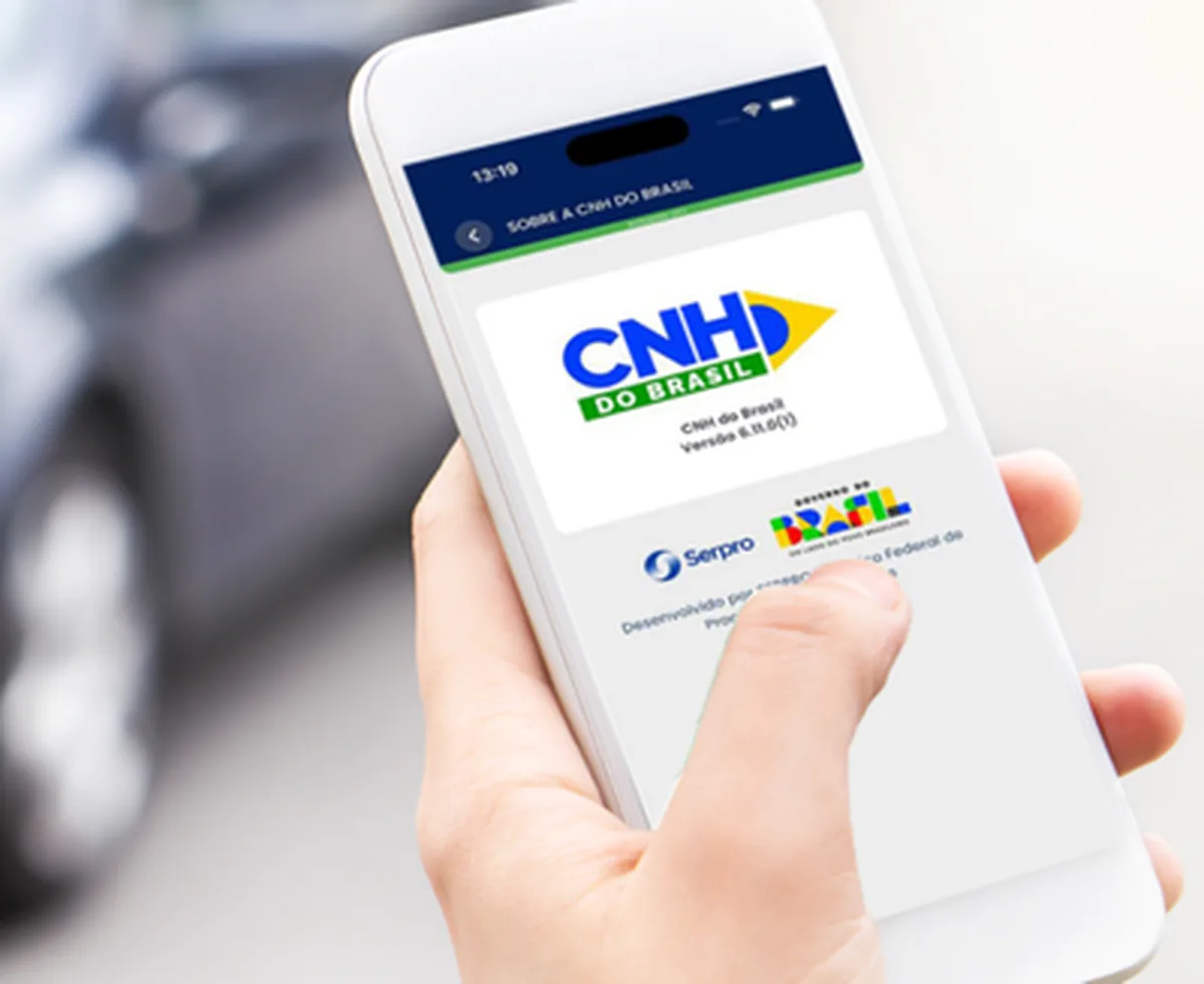 Detalhe de uma mão segurando um celular cuja tela exibe o app CNH do Brasil em funcionamento