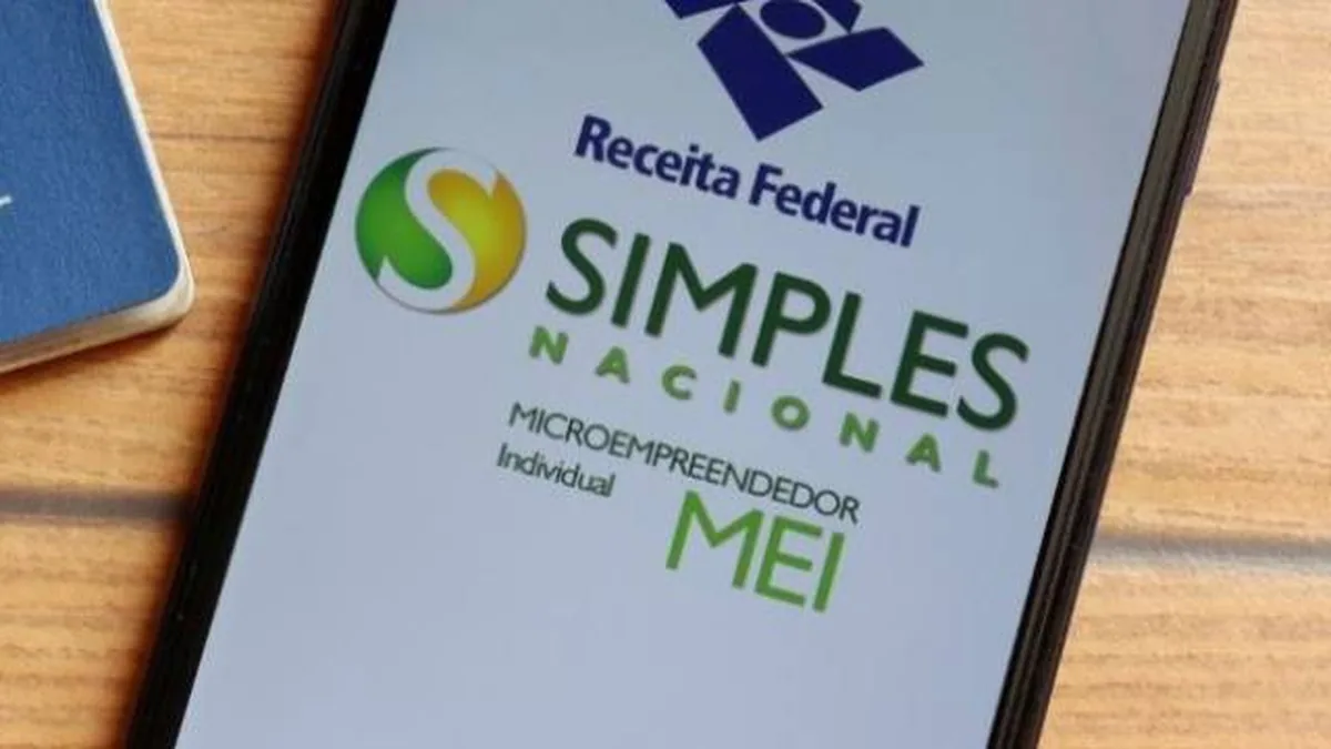 Tela de celular exibindo o logo da Receita Federal e os dizeres Simples Nacional e Microempreendedor Individual MEI em fundo branco, com um caderno azul ao lado